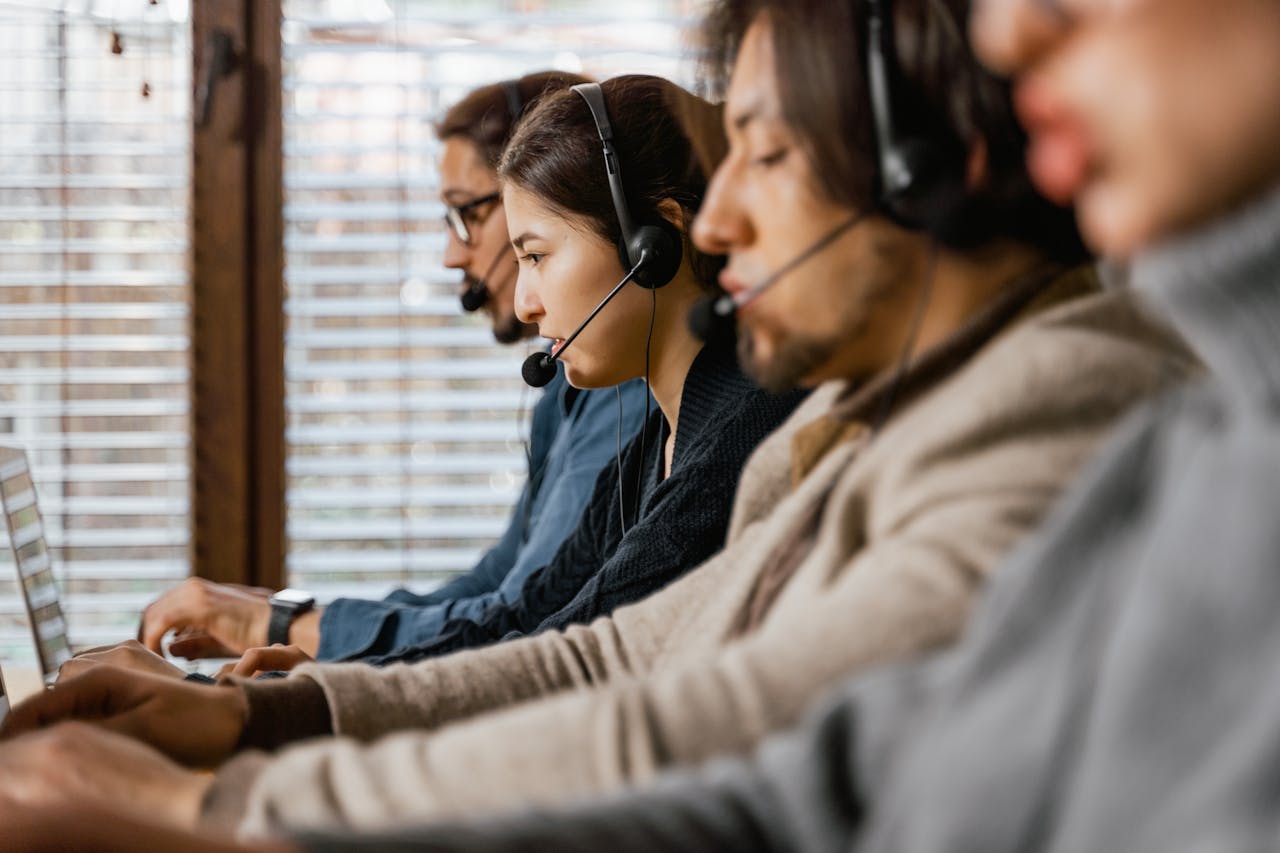 Focused customer support team using headsets and laptops in a busy office setting.