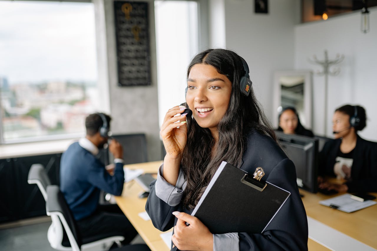 A smiling call center agent with headphones works in a modern office.